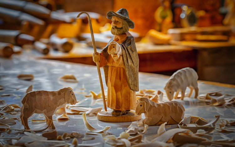 Holzschnitzerei eines Hirten mit Schafen auf einem Tisch voller Späne