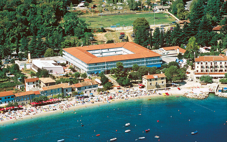 Luftaufnahme eines Küstenhotels mit Strand und umliegender grüner Landschaft.