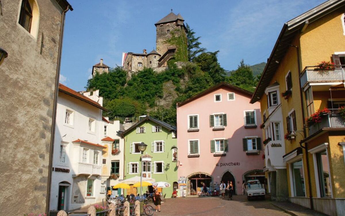Altstadtplatz mit bunten Häusern und Schloss Branzoll im Hintergrund in Klausen, Südtirol.
