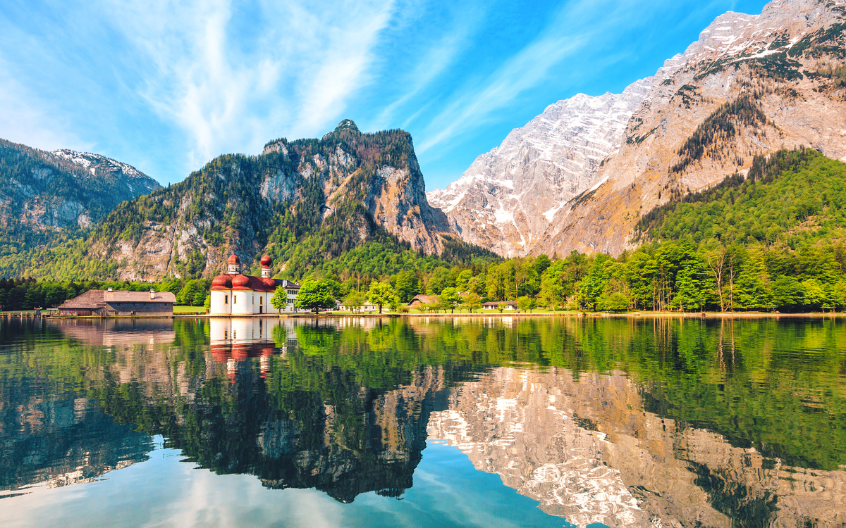 Berglandschaft mit Kirche am Seeufer und Spiegelung im Wasser