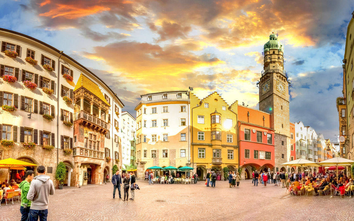 Historischer Platz mit bunten Gebäuden und Turm bei Sonnenuntergang.