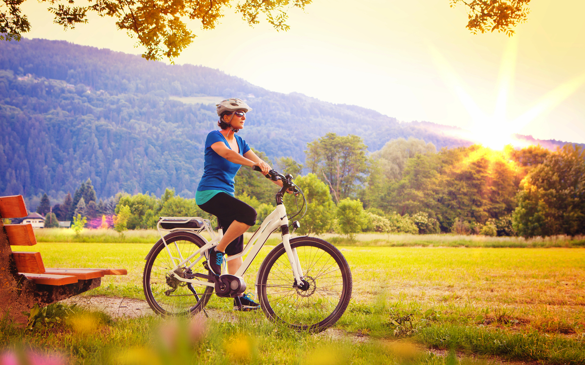 Person auf E-Bike vor Landschaft bei Sonnenuntergang