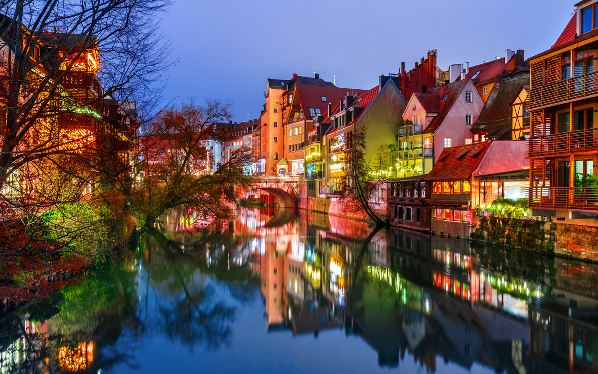 Malerische Stadtansicht mit Fachwerkhäusern am Fluss bei Dämmerung.